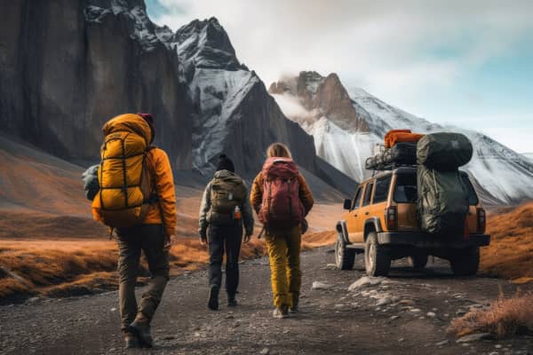 tree people wearing hiking gear and backpacks, walking on a mountain road next to a jeep